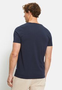 Navyblaue Baumwoll-T-Shirt mit kurzen Ärmeln, Rundhalsausschnitt, glatter Textur und einem dezenten Logodetail an der Seitennaht.