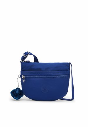 Blauwe crossbodytas met verstelbare band, voorvak met rits en een kleine harige sleutelhanger bevestigd aan de ritssluiting.