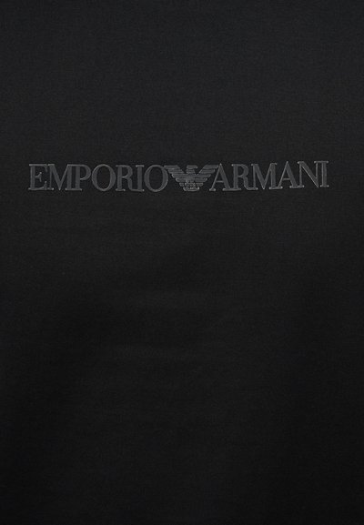 Μαύρο ύφασμα με ανάγλυκτο σκοτεινό γκρι κείμενο Emporio Armani και λογότυπο αετού τοποθετημένα οριζόντια στο κέντρο.