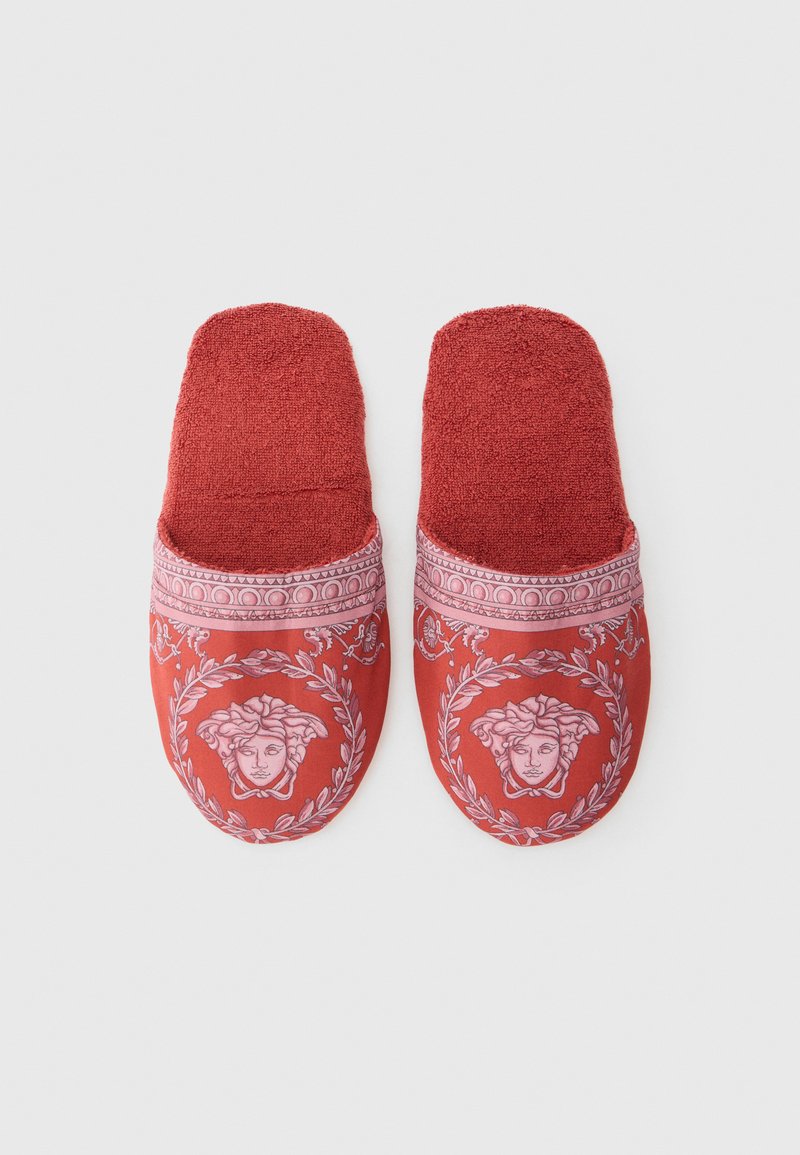 Red slipper design featuring a textured upper with a textile finish, adorned with a pink print of a head and floral motifs.