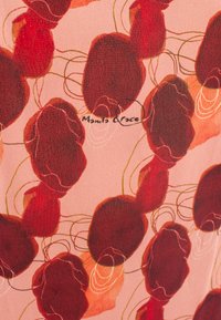 Tessuto a fantasia con forme floreali astratte rosse su uno sfondo rosa chiaro, con delicate linee verdi e il nome del marchio "Manila Grace" visibile.