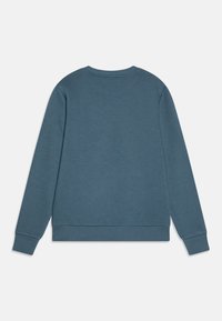 Sudadera azul con cuello redondo, mangas largas y puños y bajo acanalados. Textura suave, diseño minimalista y sin logotipos o patrones visibles.