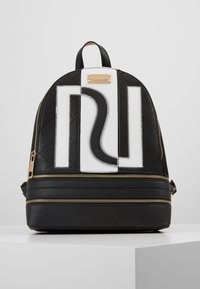 Black quilted backpack made of textured material, featuring a white logo and gold hardware, with dual zippered compartments and top handle.