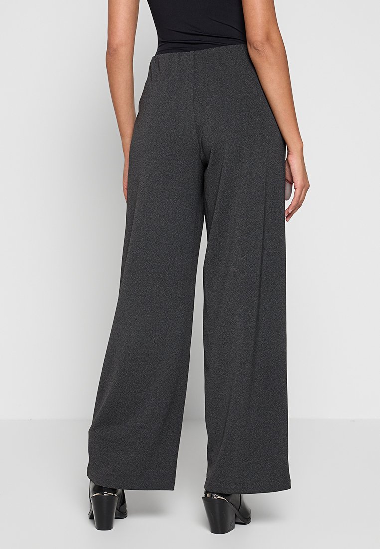 Grijze wijde broek van een gestructureerde stof, met een hoge tailleband en een relaxte pasvorm, gecombineerd met zwarte hakken.