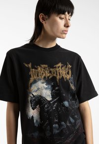 Black cotton t-shirt featuring a graphic design of a knight on a horse. The artwork includes intricate details and a distressed background.