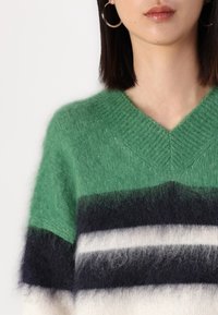 Green and navy striped sweater with a V-neck design. Soft texture, featuring dark blue, white, and light gray horizontal stripes.