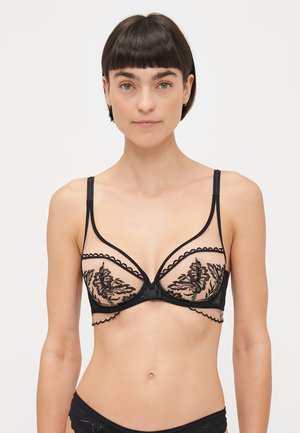Soutien-gorge en dentelle noire avec des bonnets transparents ornés de motifs floraux brodés, des bretelles réglables et une fermeture à crochets à l'avant.