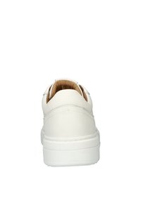 Witte leren sneaker met een ronde achterkant, gewatteerde kraag en een dikke witte rubberen zool. Het interieur heeft een tan kleurige voering.