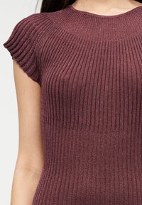 Κορυφή μπορντό ριπ πλεκτή με κοντά καπάκια μανίκια, με υφή και εφαρμοστό σχέδιο, τονίζοντας κάθετες αυλακώσεις σε όλη την επιφάνεια.