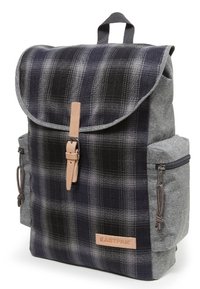 Grå och marinrandig ryggsäck med en vikbar klaff, läderlåsstängning och sidofickor. Hållbart tyg med strukturerad yta.