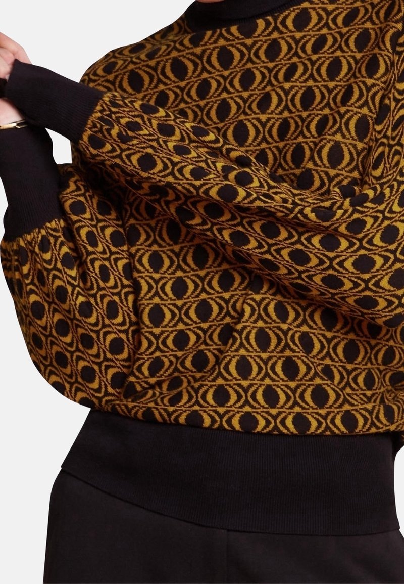 Strickpullover in Schwarz und Senfgelb mit ovalem Muster. Verfügt über lange Ärmel und einen schwarzen Rippbund für eine enge Passform.