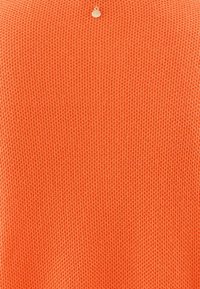 Tissu tricoté en orange vif, avec un motif texturé. Comprend un petit détail en métal argenté au centre en haut.