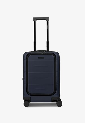 Maleta de mano rígida azul marino con bolsillo frontal con cremallera, cuatro ruedas giratorias y mango telescópico negro extendido.