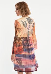 Langärmliges, mehrfarbiges Kleid mit transparentem Stoff, Palmenblattmuster und einem schwingenden Rock mit einem Farbverlauf im Sonnenuntergangsdesign.