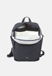 Svart ryggsäck med en mjuk yta, zippered topp och rymlig krämfärgad insida. Har justerbara remmar och en framficka för organisering.