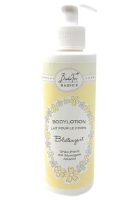 Body lotion bottle with a white pump. Circular label features yellow background with floral accents and text in black, gray, and white.