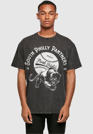 Musta, ylisuuri t-paita, jossa on valkoinen grafiikka pantterista ja teksti "South Philly Panthers" baseball-teemalla. Puuvillamateriaali.