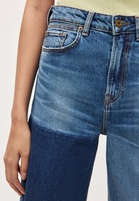 Τζιν παντελόνια από λευκό και σκούρο μπλε denim με δίχρωμο σχέδιο, ψηλή μέση, πέντε τσέπες και αντίθετες ραφές. Λείο υφή.