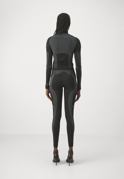 Black activewear set with a fitted long-sleeve top and leggings. Features textured patterns and a mock neck design, showcasing a sleek silhouette.