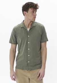 Camisa de manga corta, con cuello, en verde oliva, hecha de una tela suave, con cierre de botones en la parte delantera y un corte relajado.