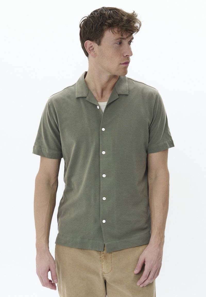 Camisa de manga corta, con cuello, en verde oliva, hecha de una tela suave, con cierre de botones en la parte delantera y un corte relajado.