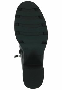 Suela de bota de goma negra con superficie texturizada, que presenta estrías horizontales para mayor agarre y un ligero tacón para estabilidad.