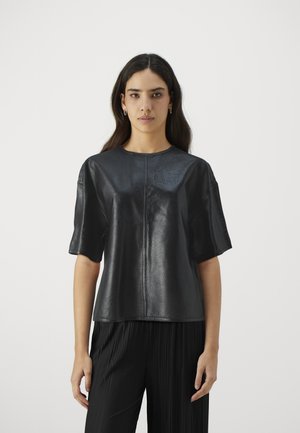 Black leather top with short sleeves, featuring a round neckline and textured surface, paired with black pleated pants.