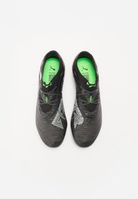 Scarpe sportive nere con design testurizzato, soletta verde e logo bianco a contrasto. Caratterizzate da lacci e una forma aerodinamica.