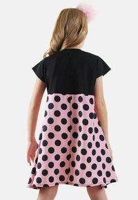 Robe noire à manches courtes avec un bas rose et de grands pois noirs. Coupe décontractée, tissu doux et col rond.