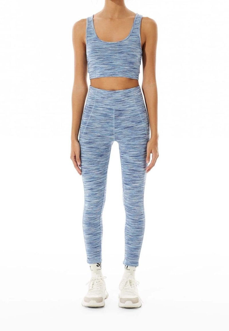 Ljusblå, strukturerad sport-bh och hög midja leggings, båda med en melerad mönster, ihop med vita träningsskor.