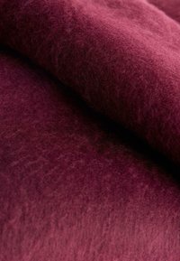 Burgundy ulltyg med en mjuk, texturerad yta som visar milda färgvariationer och en något luddig framtoning.