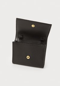 Carteira de couro preto com acabamento texturizado, apresentando um fecho por botão de pressão e dois compartimentos interiores para cartões. Design aberto e funcional.