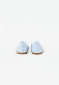 Ballet flats bleu clair avec une texture lisse semblable au cuir, bout rond et un petit talon marron, présentant des détails de couture subtils.
