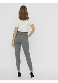 Szare, zwężane spodnie z miękkiego materiału, wysoki stan z eleganckim krojem, zestawione z dopasowaną białą górą i czarnymi szpilkami.