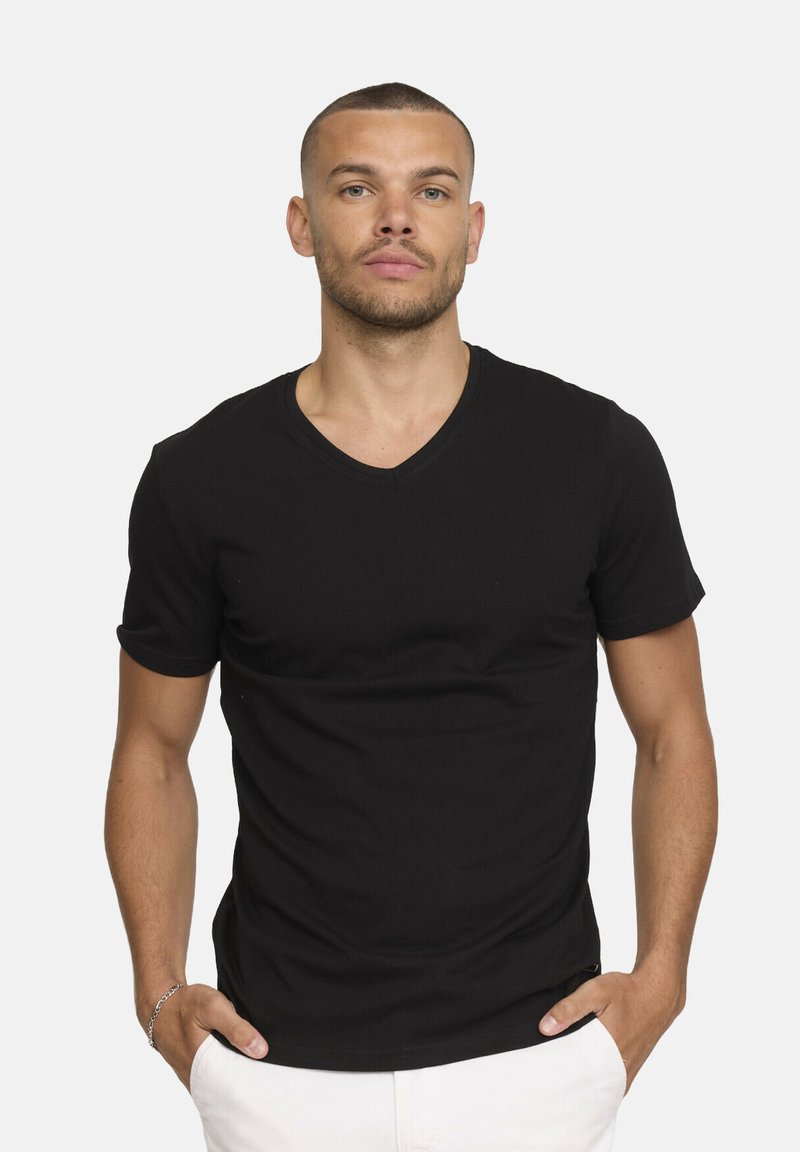 T-shirt noir à manches courtes et décolleté en V, fabriqué en tissu coton à la texture lisse, au design ajusté et avec un minimum de détails de couture.