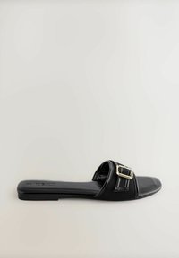 Sandale plate noire à enfiler avec une large bride unique ornée d'une boucle dorée et un design à bout carré.