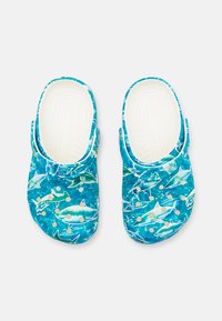 Modré dřeváky se vzorem žraloka, s texturovanou stélkou, zadním popruhem a světlými akcenty. Vyrobeny z lehkého materiálu.