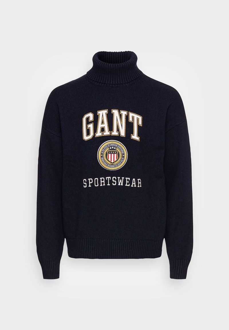 Maglione a collo alto lavorato a maglia blu navy con il testo bianco "GANT" e "SPORTSWEAR", un design del logo circolare al centro e polsini a costine.