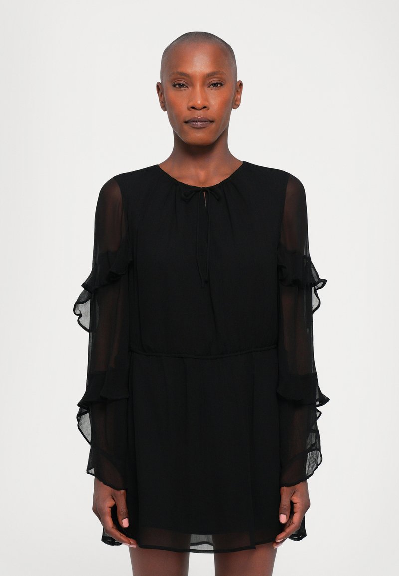 Black dress with sheer, ruffled long sleeves, round neck, and a tie closure at the collar. Flowing fabric with a loose fit.