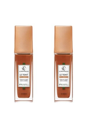 Deux bouteilles de fond de teint avec un design en verre rectangulaire. Liquide marron à l'intérieur, chacune ayant un capuchon en bronze carré et une étiquette affichant les détails du produit.