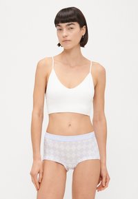 Fehér szövet bralette vékony pántokkal, ami világoslila mintás hipster alsóneművel van párosítva, amelynek derékrészén a "PIECES" felirat szerepel.