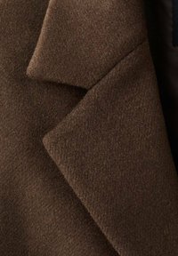 Tessuto per cappotto di lana marrone, caratterizzato da una superficie morbida e testurizzata e un design a rever strutturato, che mostra un colore profondo e ricco e una finitura senza cuciture.