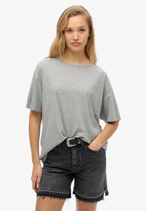 T-shirt grigio chiaro a maniche corte in una vestibilità rilassata, abbinato a pantaloni shorts in denim neri a vita alta con orli sfilacciati e una cintura con fibbia in argento.