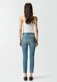 Jean skinny bleu clair taille haute, avec des détails brodés sur les poches arrière et un tissu légèrement extensible.