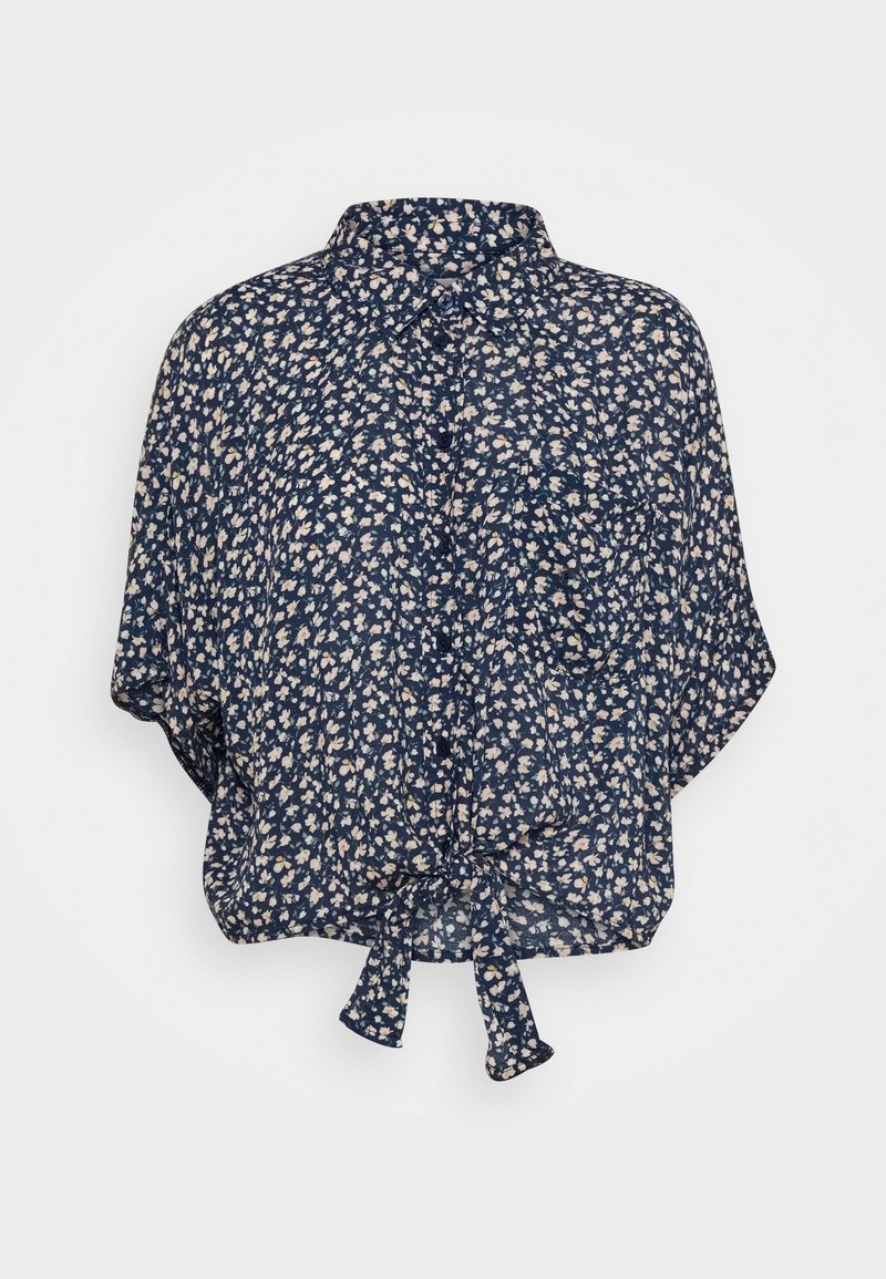 Blouse bleu marine à manches courtes avec petit imprimé floral blanc, boutons devant, poche poitrine et nœud noué à l’ourlet.