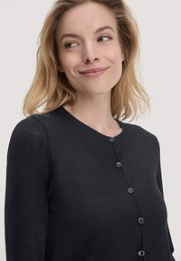Schwarze Strickjacke mit Rundhalsausschnitt, langen Ärmeln und Knopfverschluss. Sie hat eine glatte, weiche Textur und einen subtilen Glanz.