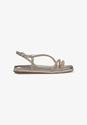 Sandalias metálicas doradas con suela plana, correa ajustable en el tobillo y parte superior entrecruzada texturizada con acentos decorativos de cuentas.