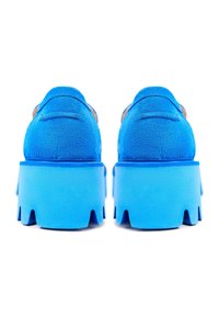 Paire de chaussures compensées en daim bleu vif avec des semelles épaisses et crantées, vues de dos sur fond blanc.
