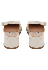 Sandali platform beige con punta aperta, cinturino alla caviglia e una finitura liscia. Il tacco è più spesso, garantendo stabilità e comfort.