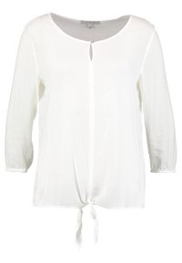 Blusa blanca, ligera, de manga larga con cuello redondo y detalle de lazo en la parte frontal. Presenta un pequeño corte en forma de llave en el cuello.
